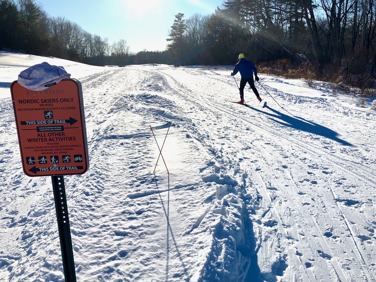 a photo of a cross country skier skiing away from the viewer into low sunlight