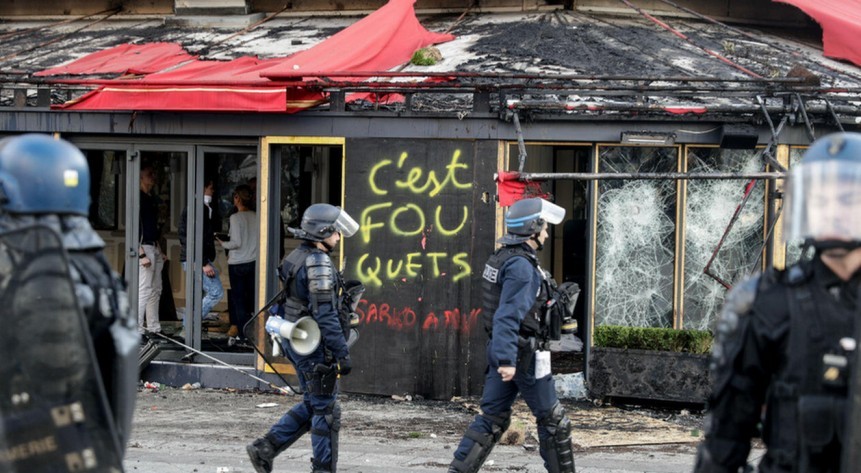 The Fouquets, a Parisian restaurant where right wing politician love dining, with its roof blackened by fire, its windows broken, and tags on ("C'est Fou-quets", "c'est fou" meaning "it's crazy!"). Cops outide, protesters inside.